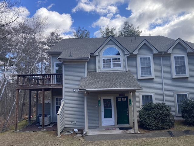 view of front of property with central AC unit, roof with shingles, and a deck