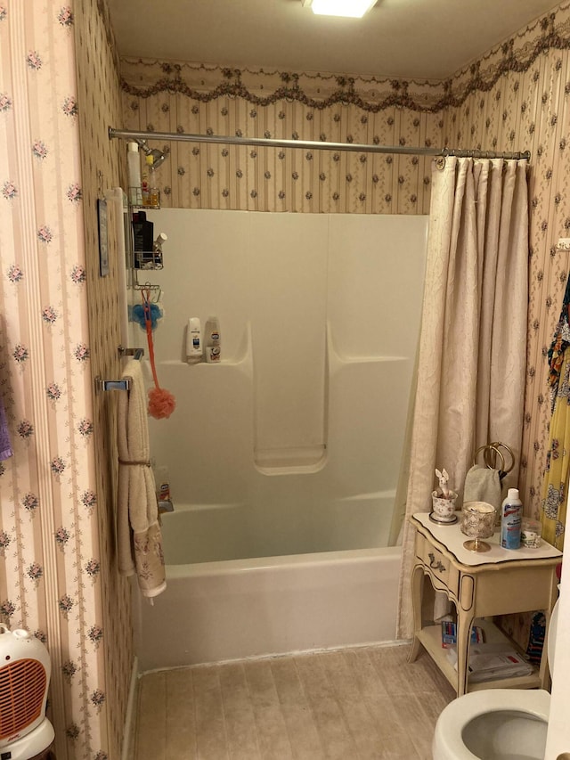 bathroom with wallpapered walls, toilet, and shower / bath combo