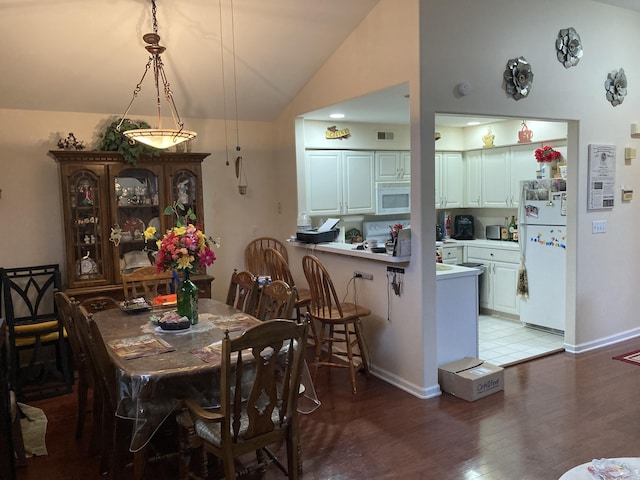 dining room with visible vents, baseboards, light wood-style floors, and vaulted ceiling