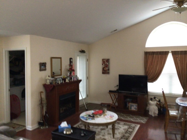 living area with visible vents, ceiling fan, vaulted ceiling, a fireplace, and wood finished floors