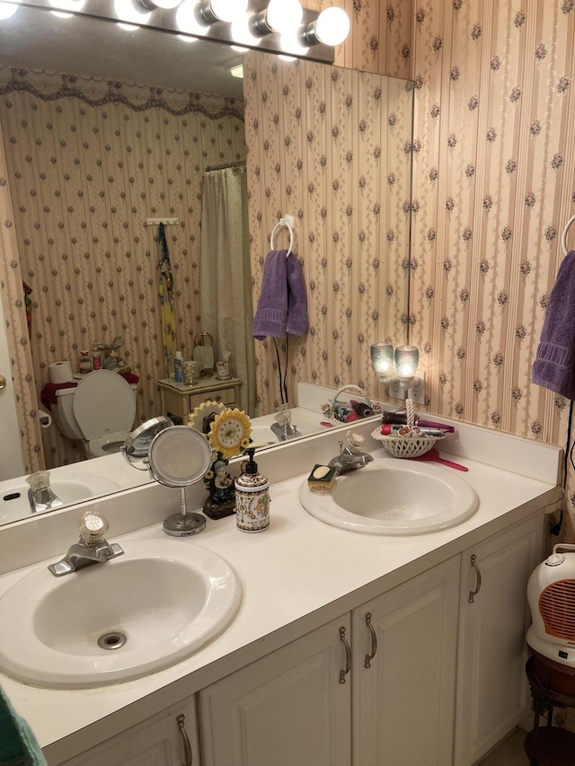 full bathroom with double vanity, wallpapered walls, a shower with shower curtain, and a sink