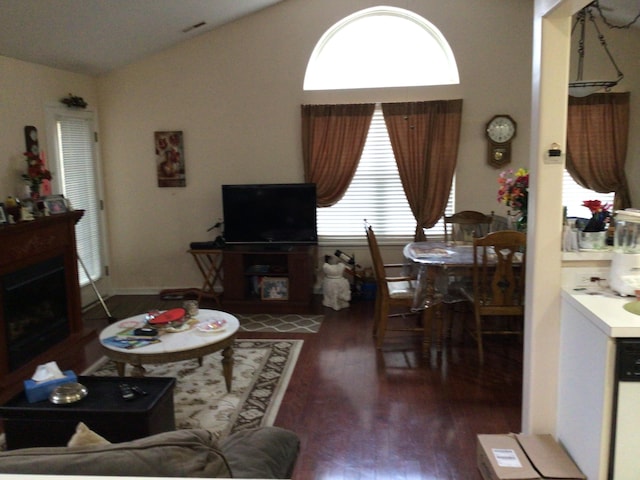 living area featuring visible vents, lofted ceiling, wood finished floors, and a fireplace