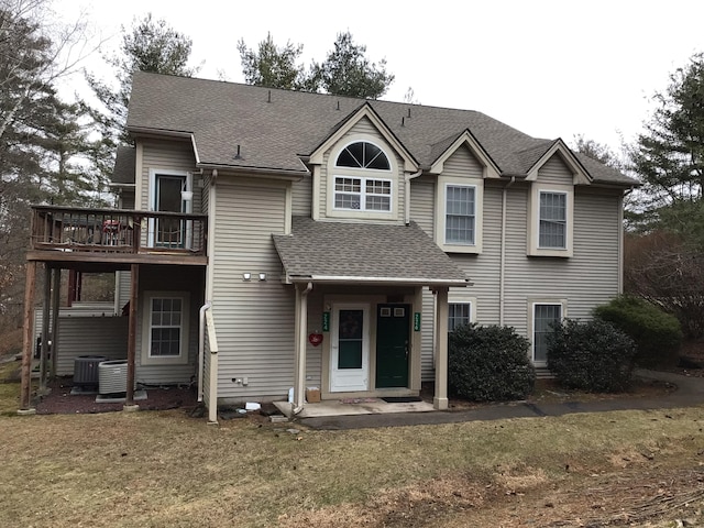 view of front of home with central air condition unit, roof with shingles, and a front lawn