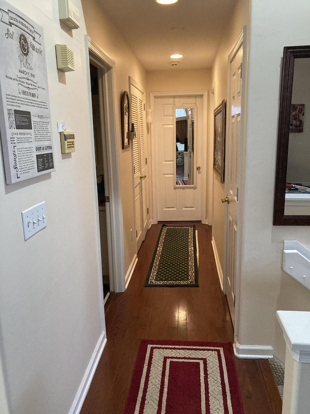 hallway featuring baseboards and dark wood-style flooring