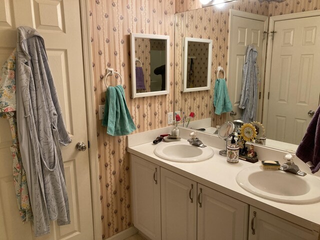 full bathroom featuring a sink, double vanity, and wallpapered walls