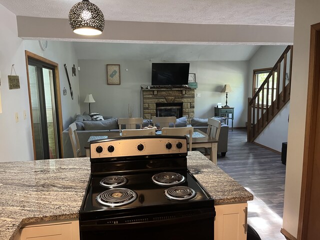 1076 Knollwood Dr, Tobyhanna, PA 18466 - kitchen with black electric range oven, open floor plan, dark wood finished floors, a stone fireplace, and white cabinetry