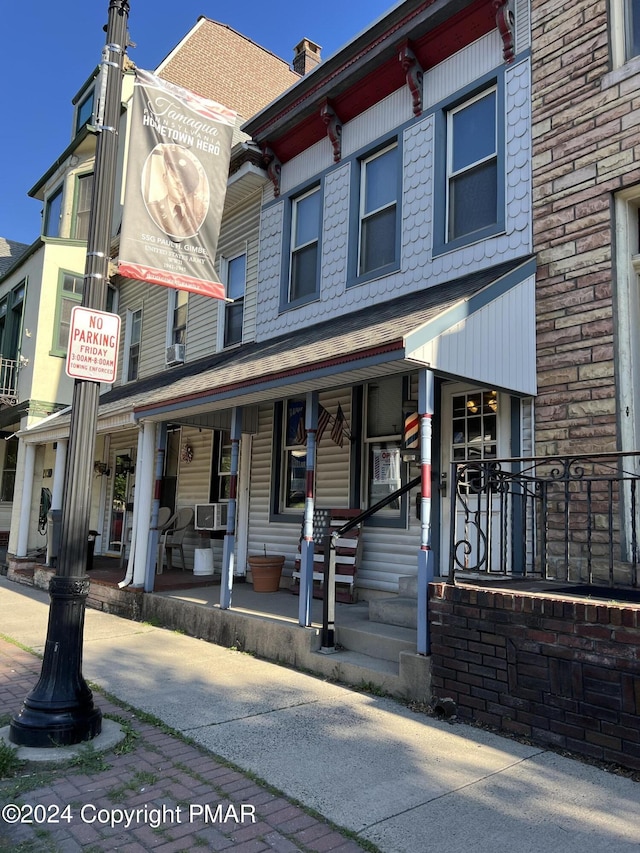 view of front of property featuring covered porch, a chimney, and cooling unit