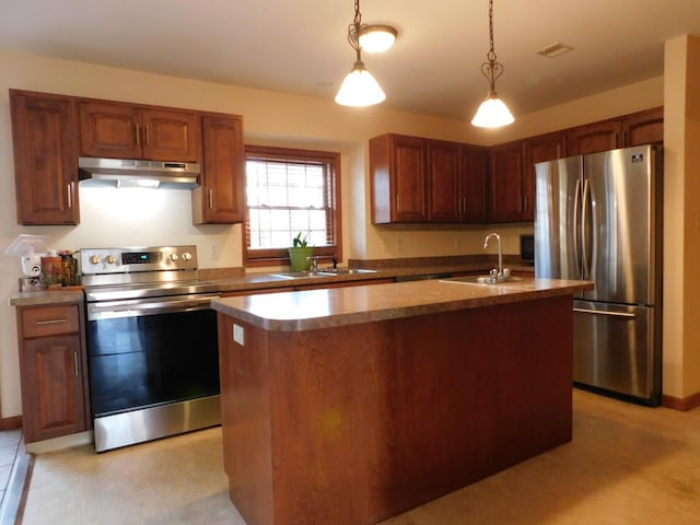 kitchen with a sink, pendant lighting, under cabinet range hood, and stainless steel appliances