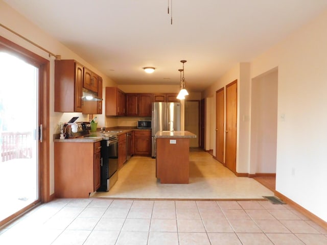 kitchen featuring under cabinet range hood, light countertops, appliances with stainless steel finishes, and a center island