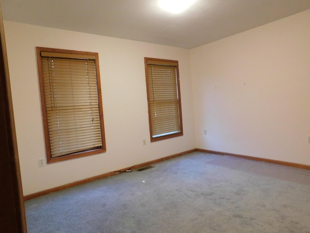 carpeted spare room featuring visible vents and baseboards