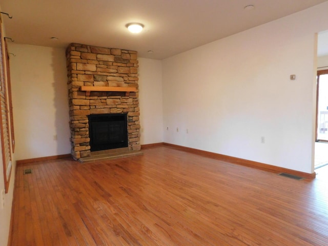 unfurnished living room featuring visible vents, a fireplace, baseboards, and wood finished floors