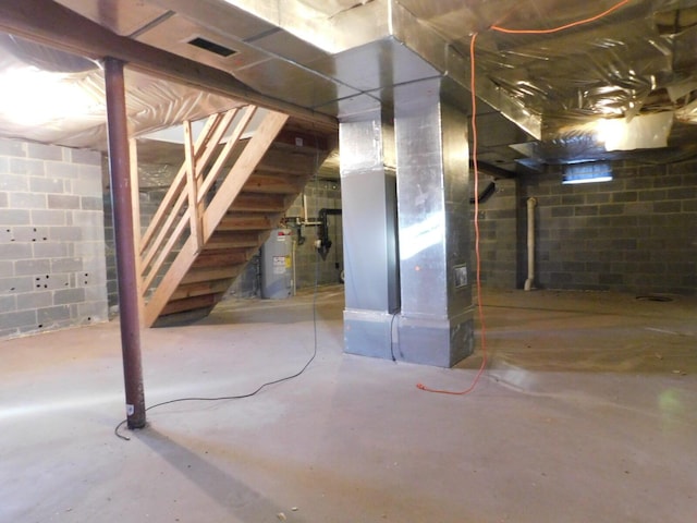 unfinished below grade area featuring visible vents, electric water heater, and concrete block wall