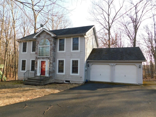 colonial house with aphalt driveway, stone siding, and an attached garage