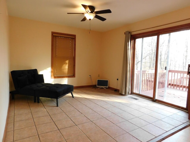 sitting room with light tile patterned floors, visible vents, baseboards, and ceiling fan