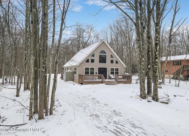 snow covered back of property with a wooden deck