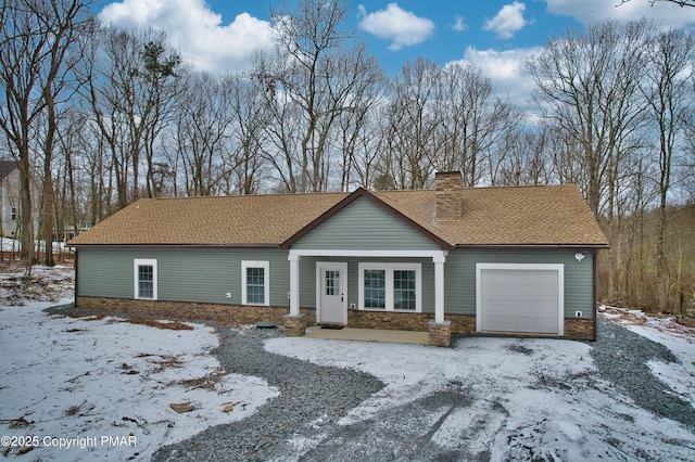 view of front of home with stone siding, an attached garage, a chimney, and a shingled roof