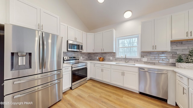 kitchen featuring tasteful backsplash, vaulted ceiling, appliances with stainless steel finishes, and a sink