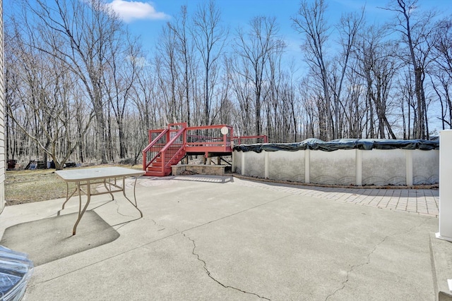 view of patio featuring a deck, stairway, and a covered pool