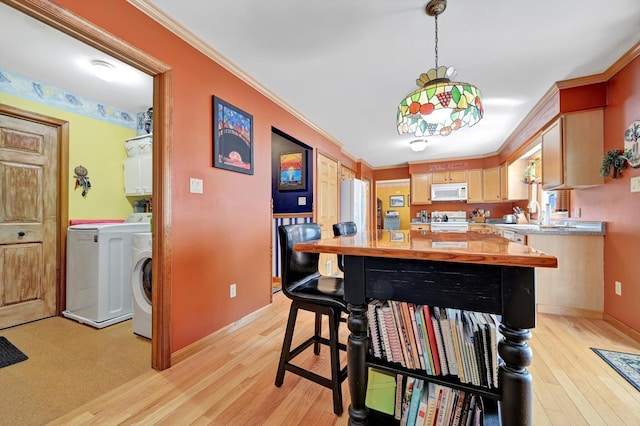 kitchen with light wood finished floors, white appliances, washing machine and dryer, and ornamental molding