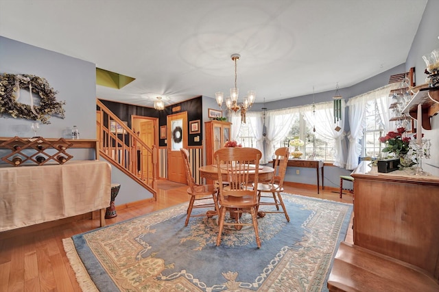 dining area with stairs, a notable chandelier, and wood finished floors