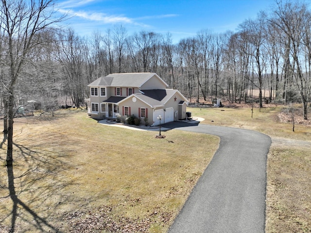 traditional-style house featuring a front lawn, an attached garage, and driveway