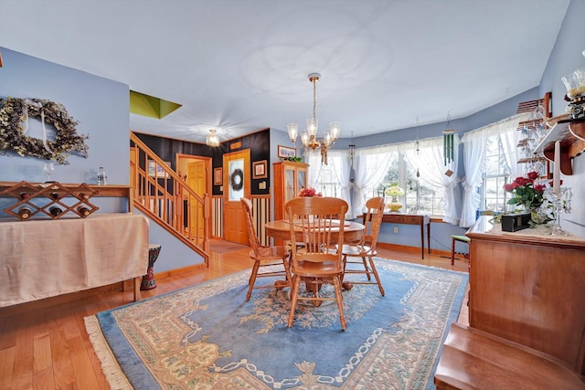 dining area with stairway, a notable chandelier, and wood finished floors