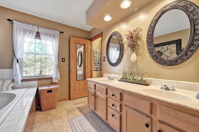 full bathroom with a sink, baseboards, double vanity, and tiled bath