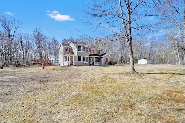 view of front of house with a garage, covered porch, an outdoor structure, and a front yard