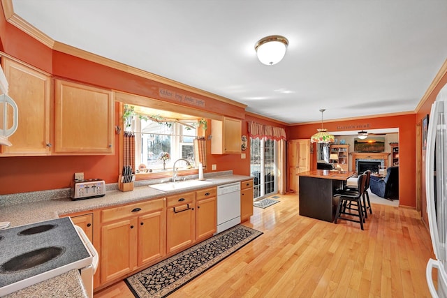 kitchen featuring white appliances, a sink, light countertops, light wood-style floors, and crown molding