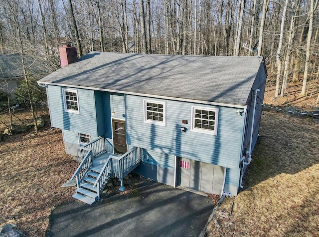 view of front of property with driveway, a carport, roof with shingles, and a chimney