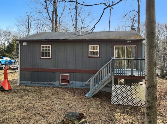 rear view of property with a shingled roof, stairway, and a wooden deck