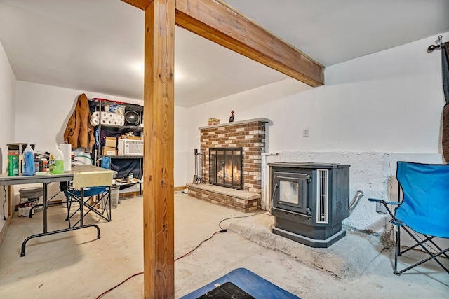 living area with beamed ceiling, concrete flooring, and a wood stove