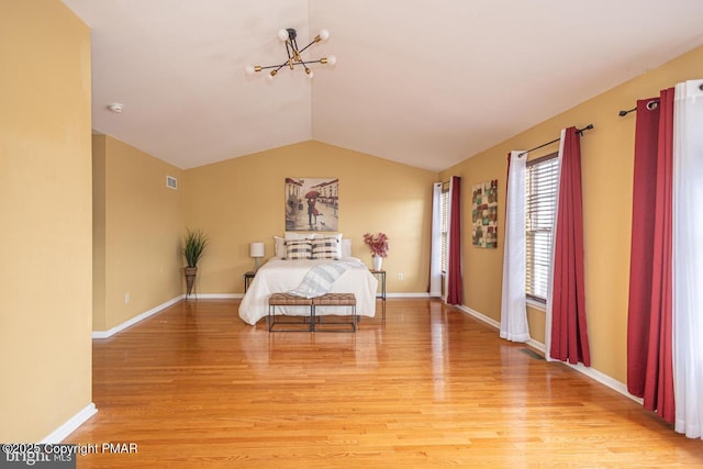 unfurnished bedroom featuring an inviting chandelier, vaulted ceiling, and light hardwood / wood-style flooring