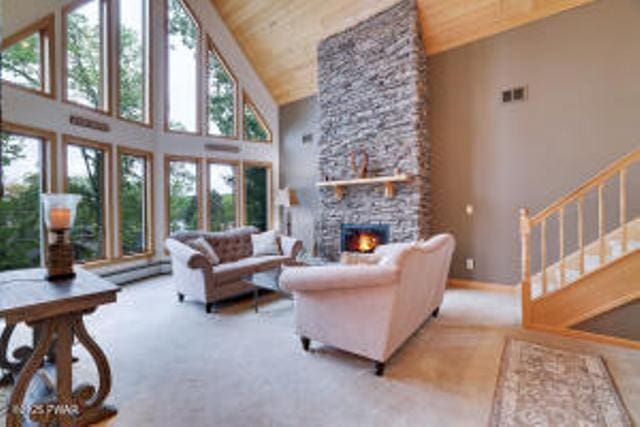 7 Shore Line Dr, Lakeville, PA 18438 - carpeted living room featuring high vaulted ceiling, wooden ceiling, a stone fireplace, and stairs