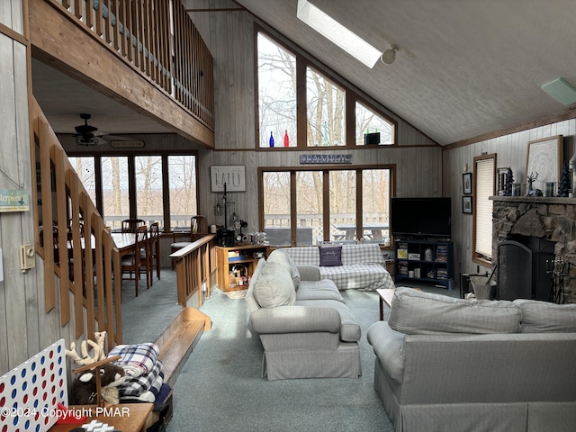 living room with carpet floors, a skylight, a healthy amount of sunlight, and a stone fireplace