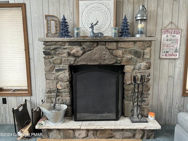 interior details featuring wood walls and a stone fireplace