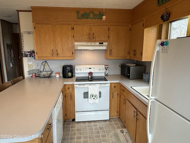 kitchen with a peninsula, white appliances, under cabinet range hood, and light countertops