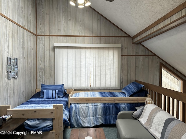 bedroom featuring wooden walls, vaulted ceiling, and a textured ceiling