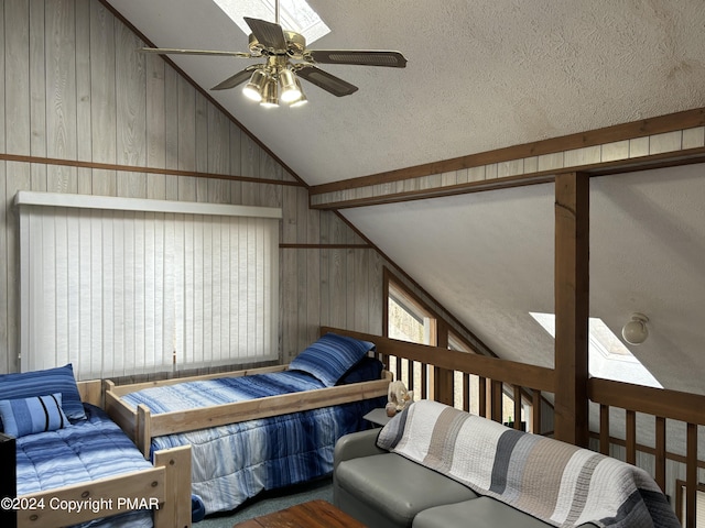 bedroom with ceiling fan, wooden walls, vaulted ceiling, and a textured ceiling