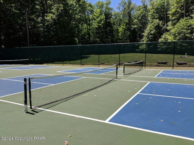 view of tennis court featuring community basketball court and fence