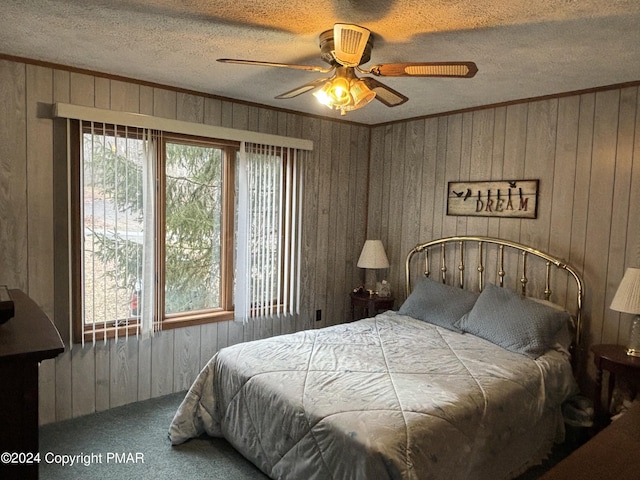 carpeted bedroom featuring a textured ceiling, ceiling fan, ornamental molding, and wood walls