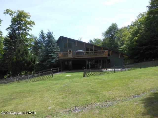 back of property featuring a yard, a deck, and fence