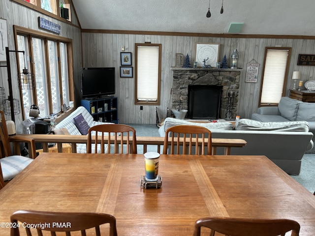 carpeted dining space featuring crown molding, a fireplace, vaulted ceiling, and a textured ceiling