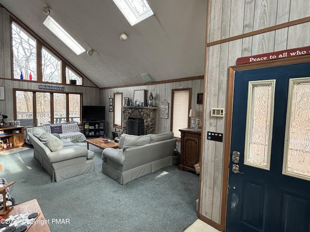 living room with a skylight, wooden walls, carpet floors, a fireplace, and high vaulted ceiling