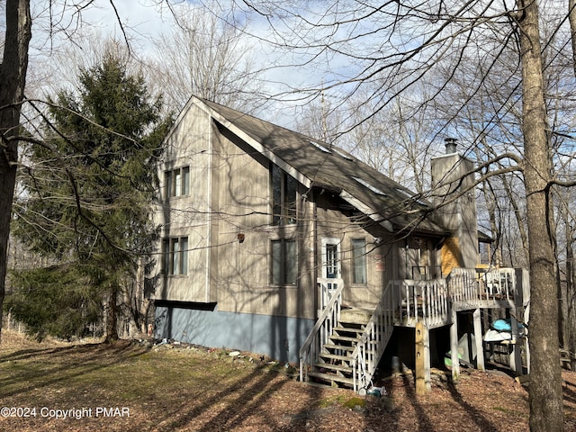 view of side of property with a chimney, stairway, and a wooden deck