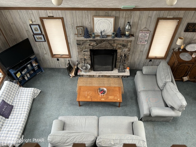 living room featuring carpet floors, wood walls, and a stone fireplace