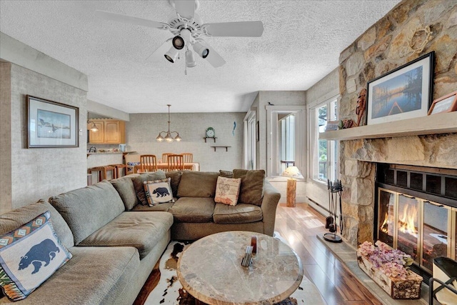 1055 Crestwoods Dr, Pocono Pines, PA 18350 - living area with a textured ceiling, ceiling fan, light wood finished floors, and a stone fireplace