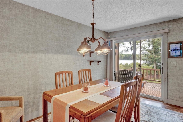 1055 Crestwoods Dr, Pocono Pines, PA 18350 - dining area with a chandelier, wood finished floors, a water view, wallpapered walls, and a textured ceiling
