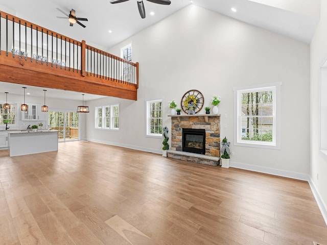 26 Susquehanna Dr, Jim Thorpe, PA 18229 - unfurnished living room with a ceiling fan, high vaulted ceiling, a stone fireplace, plenty of natural light, and light wood-style floors