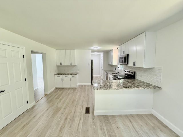 459 Pocono Blvd, Bushkill, PA 18324 - kitchen with appliances with stainless steel finishes, tasteful backsplash, light wood-type flooring, light stone countertops, and white cabinets